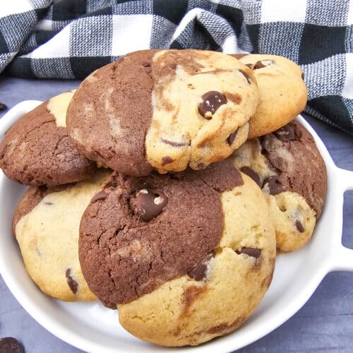 Close-up of a white dish stacked high with brookies recipe cookies showing the distinct brownie and cookie dough halves baked together.
