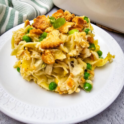 Close-up of creamy Chicken Noodle Casserole with egg noodles, shredded chicken, peas, green onions, and buttery cracker crumbs.