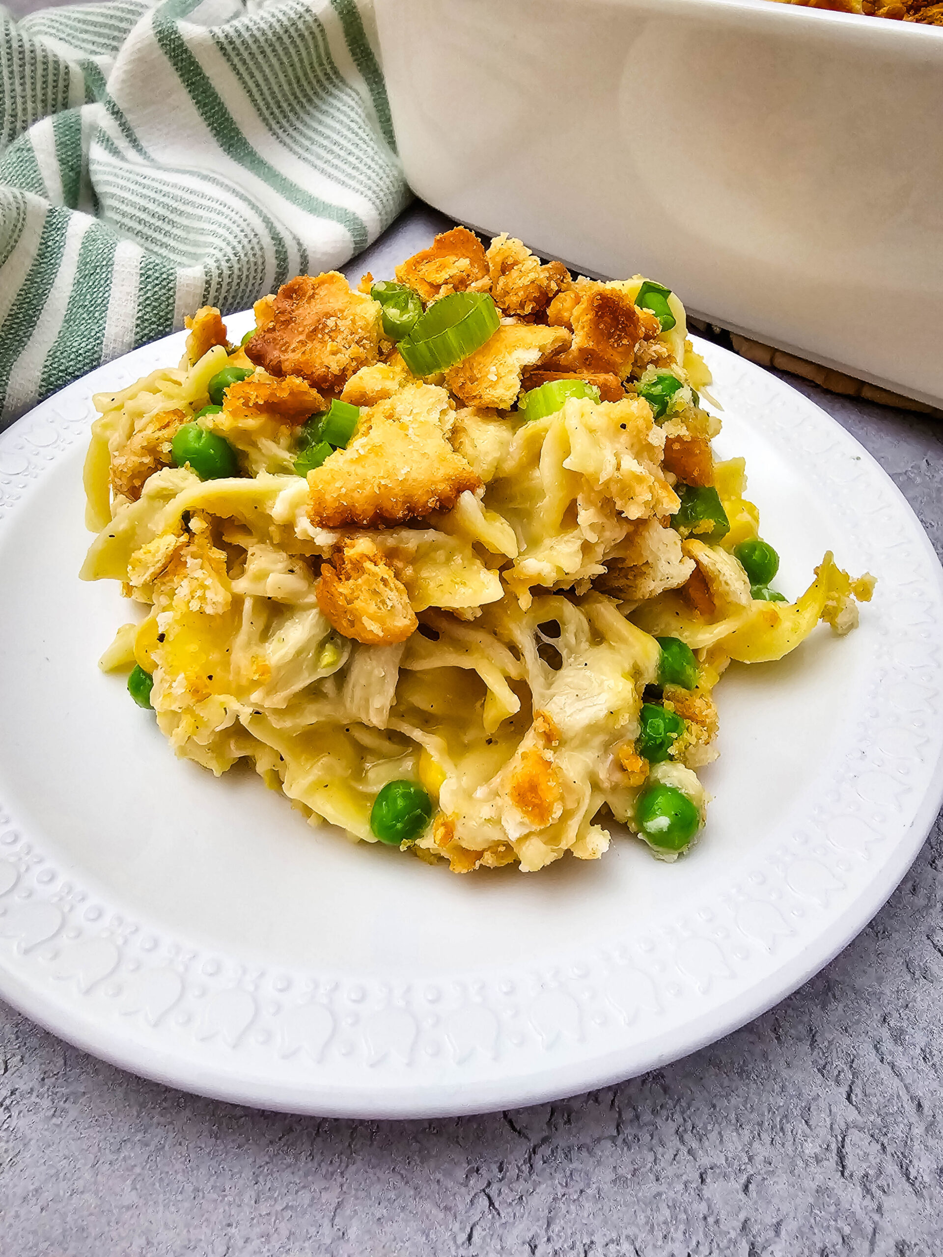 Close-up of creamy Chicken Noodle Casserole with egg noodles, shredded chicken, peas, green onions, and buttery cracker crumbs.
