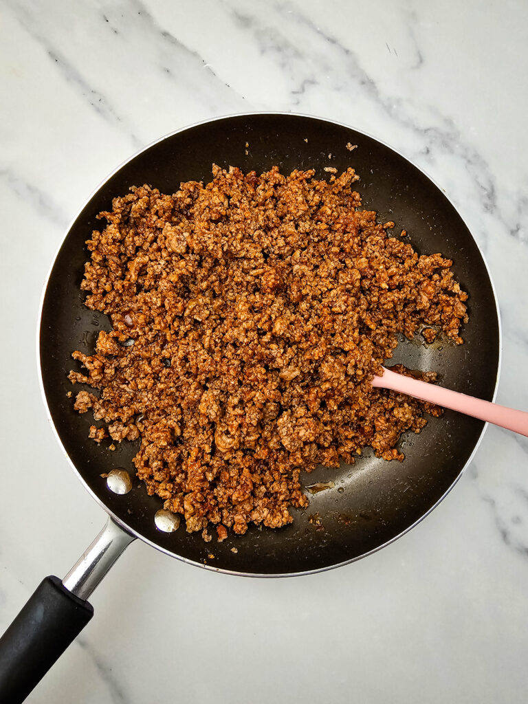 Cooked taco-seasoned ground beef in a skillet with a silicone spatula.