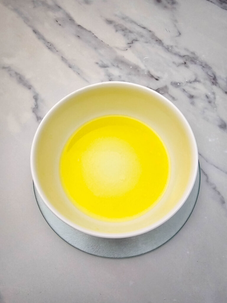 Melted butter in a small white bowl for the cracker topping.
